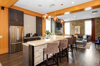 A kitchen with a large center island with a breakfast bar and a living room in the background